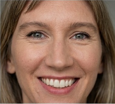 A close portrait of a woman in her thirties laughing, warm light